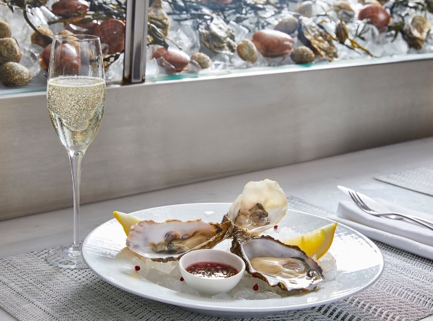 oysters on a plate with glass of champagne next to it