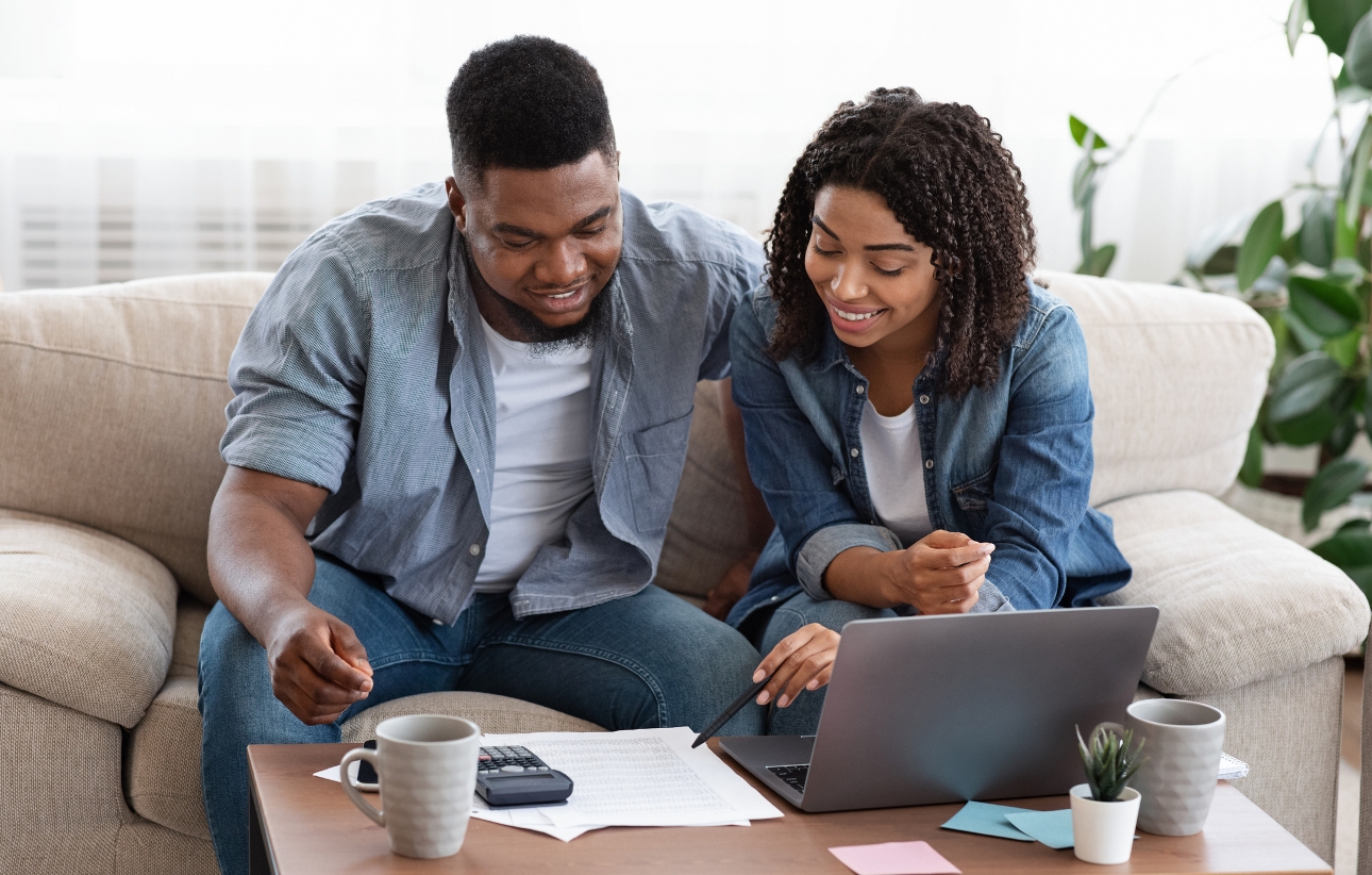 couple sat on sofa looking at lap top planning