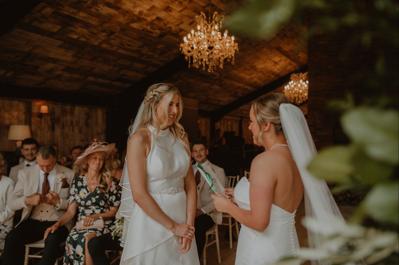 two brides during their ceremony one giving a reading