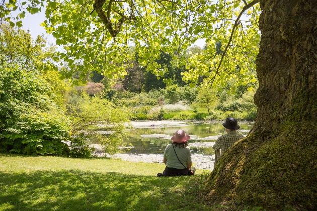 A couple sit by the lower pond in the garden at Dyrham Park 