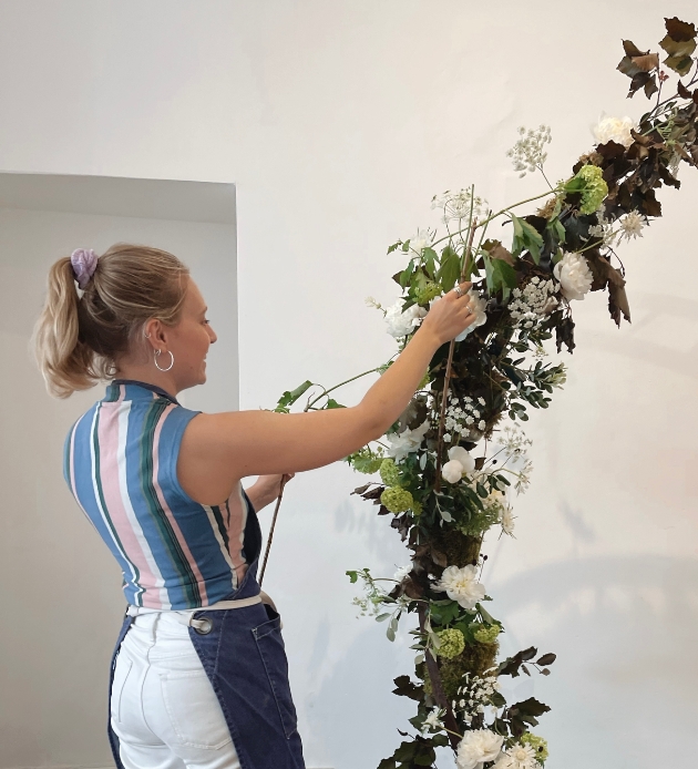 Imogen Stuckes, founder of Flowers by Imogen arranging flowers for a wedding