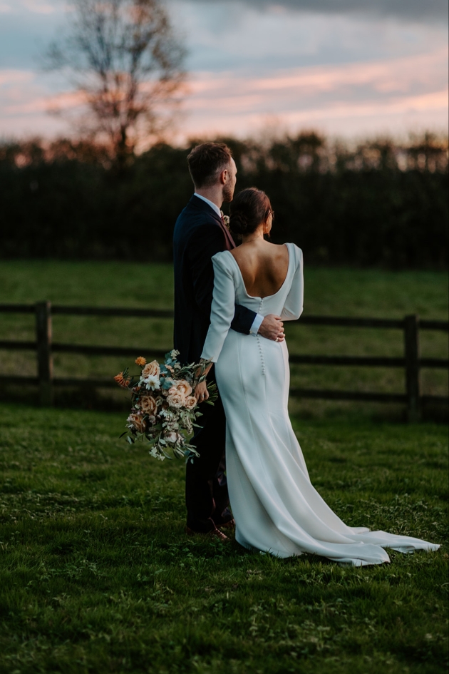 Bride and groom outdoors and dusk with their backs to the camera