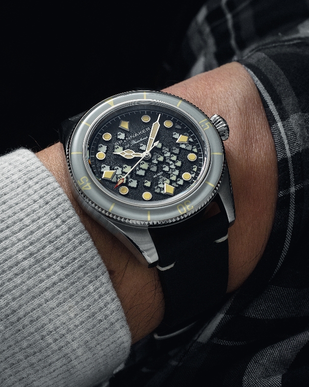 A man wearing a silver watch with little ghosts inside the clock face