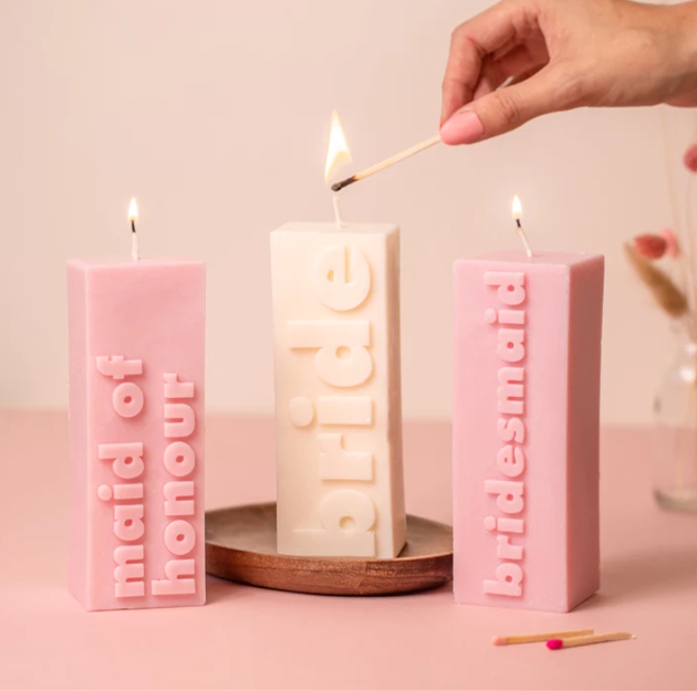 three pillar candles in pink and white with bridal party roles on