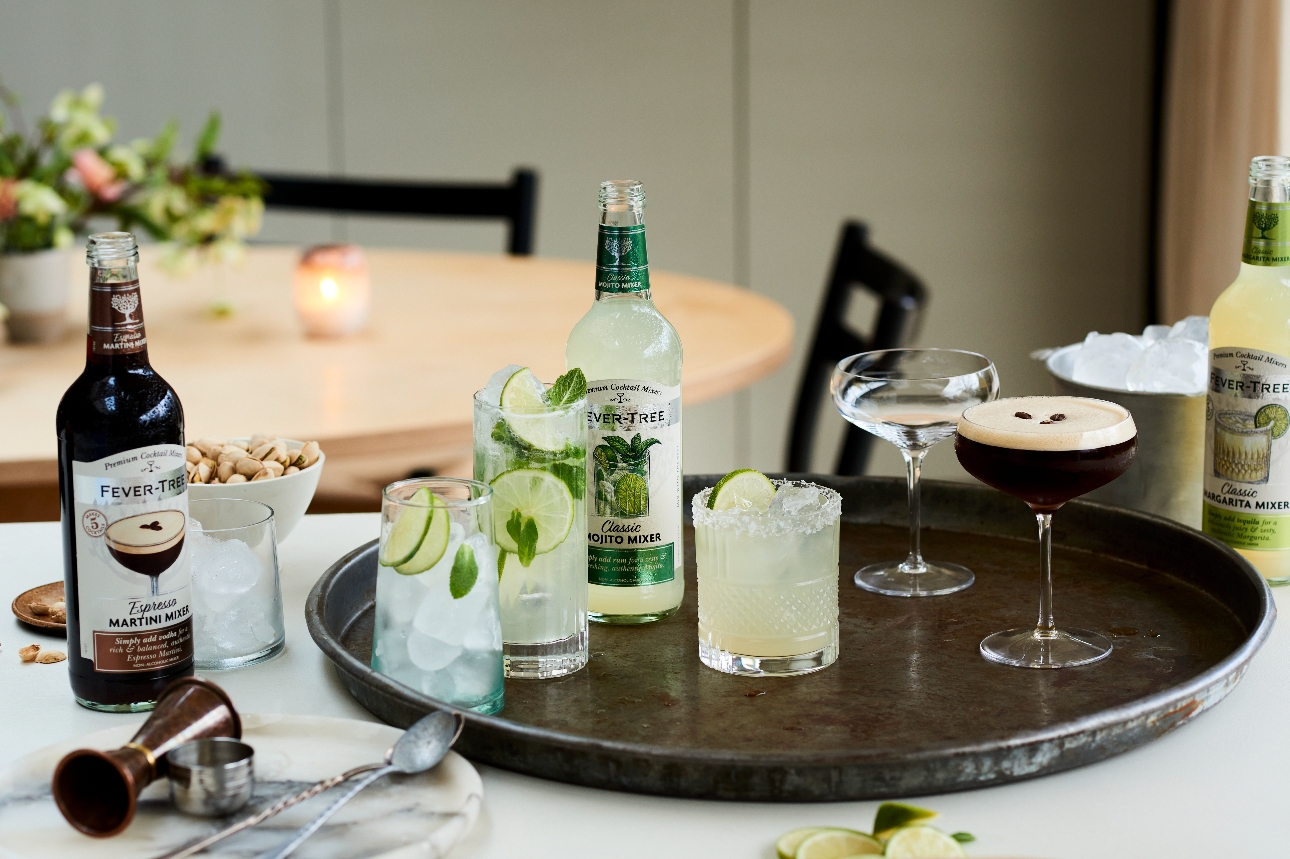 cocktails, glasses, and mixer bottle on a serving tray