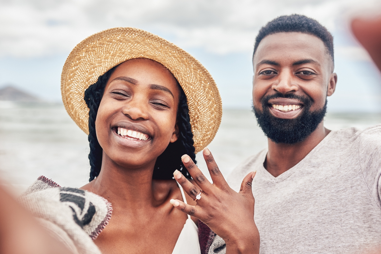 couple engaged on beach taking a selfie