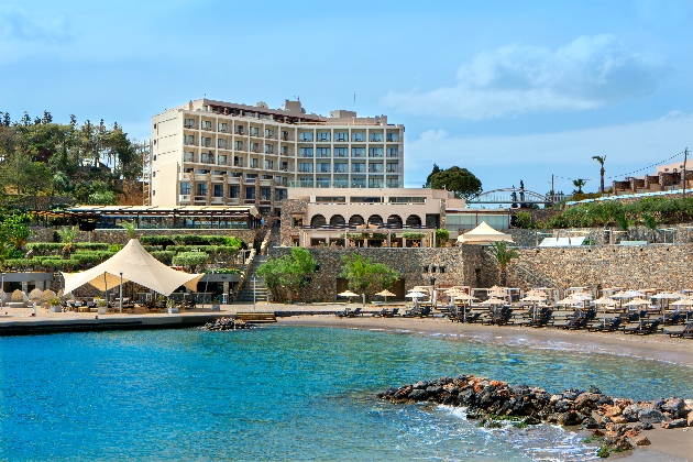 A tall white building in the distance with a beach and the sea in front of it