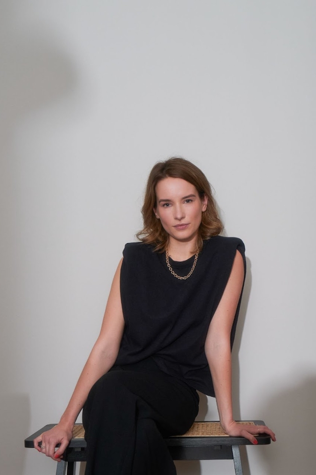 woman in black dress and gold necklace sitting down