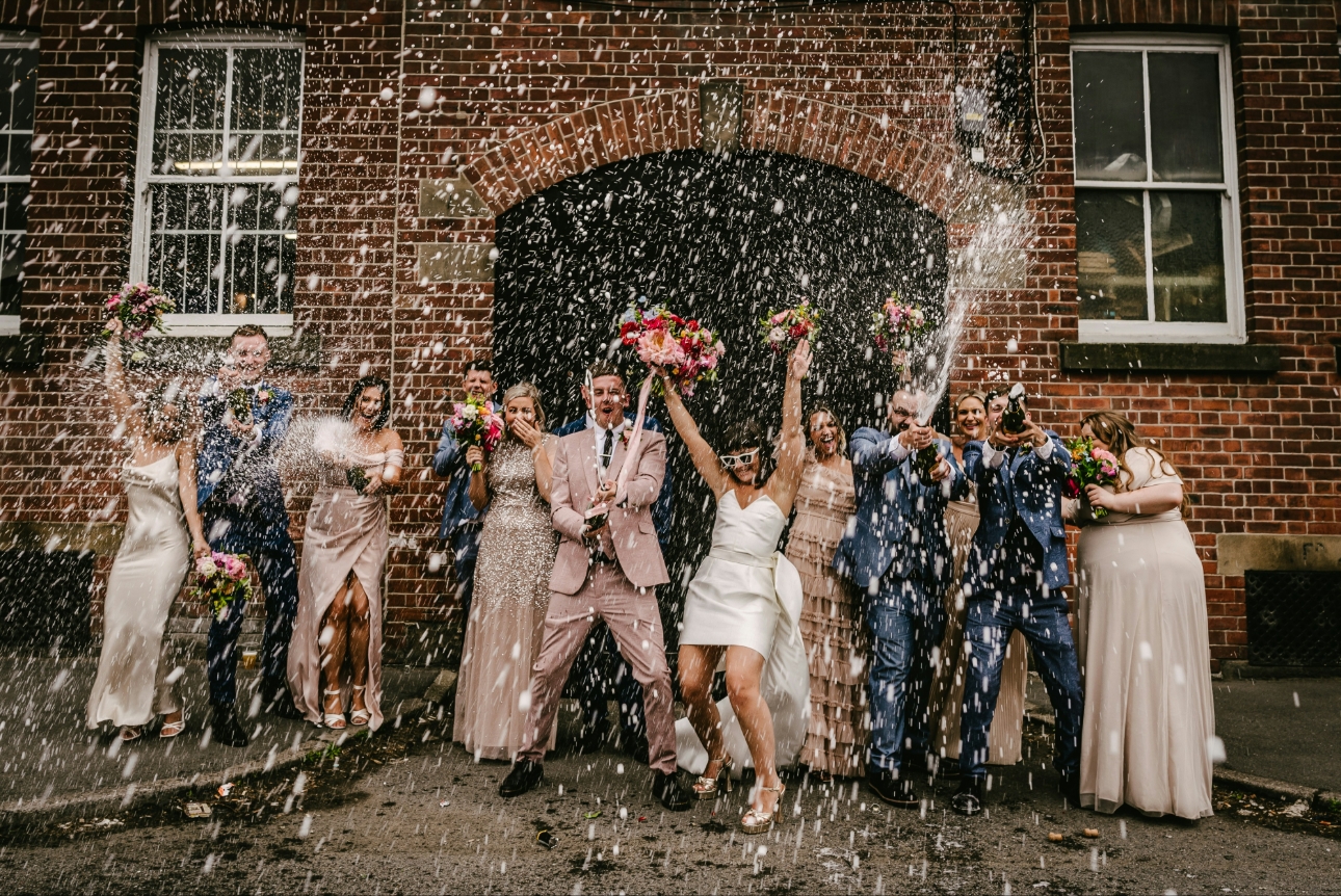 couple having confetti shot outside wedding venue